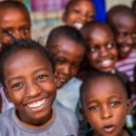 Group of colorful dressed, happy African children, orphanage in Kenya. There is no light and electricity inside the classroom. Around 20-30 orphans live in this orphanage which is located near Nairobi.